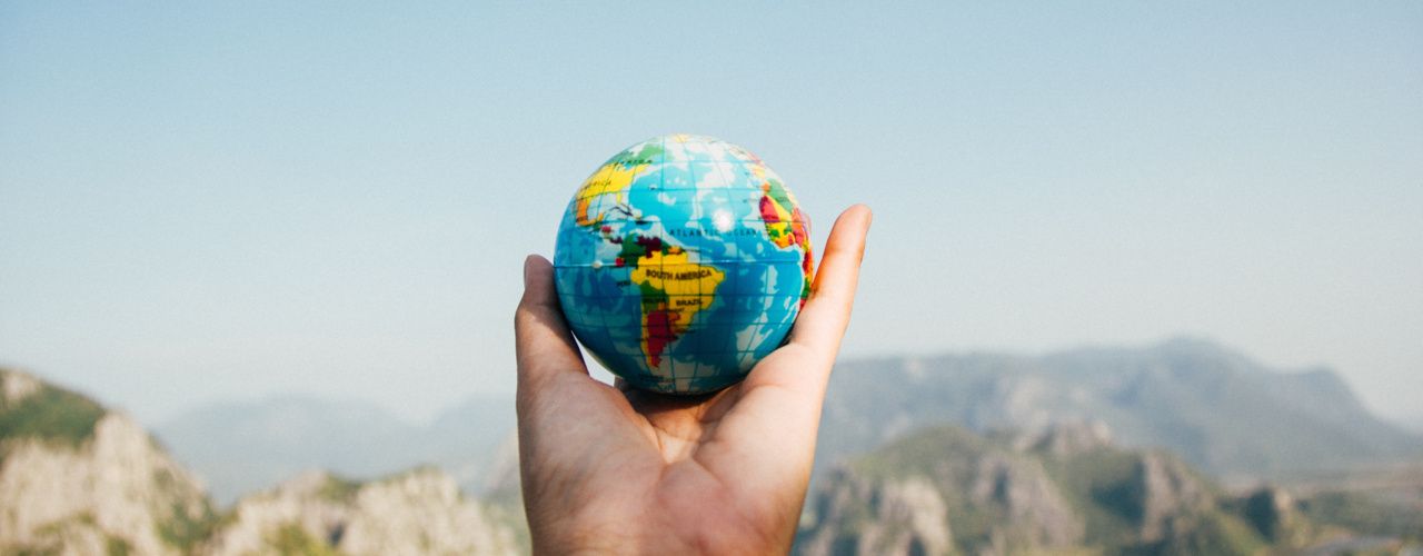 A hand holding a globe